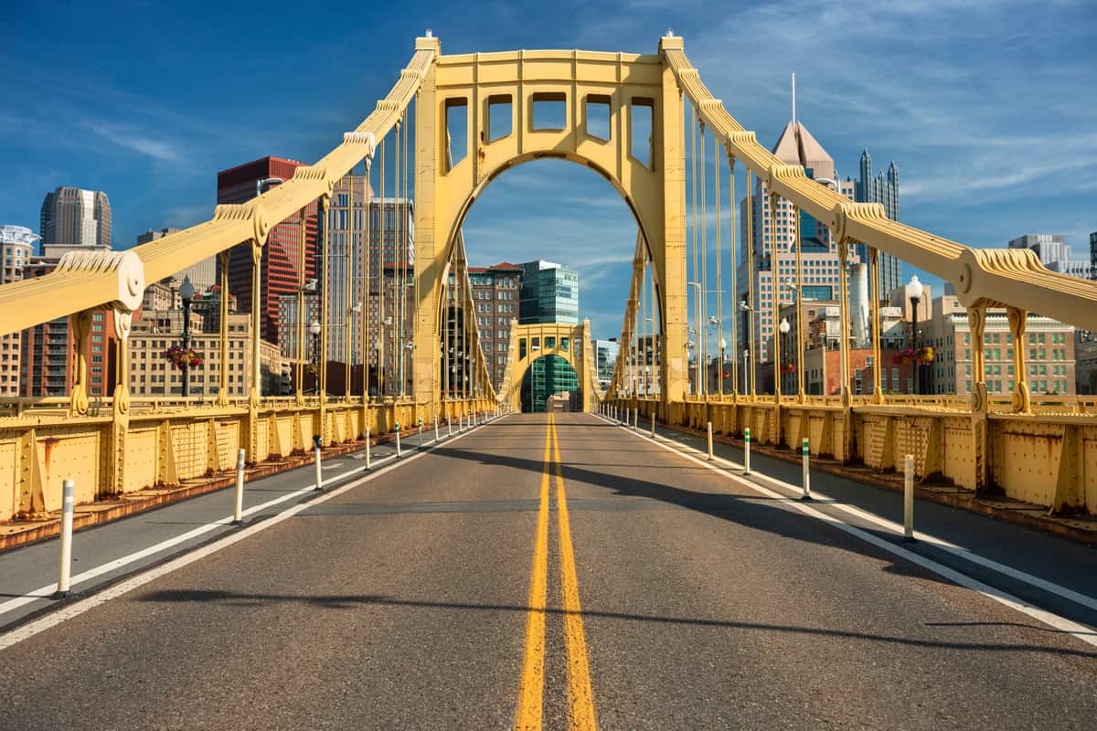 The gold-painted deck and tower of the Roberto Clemente Bridge over the Allegheny River in Pittsburgh, Pennsylvania, with the downtown skyline framed through its arch